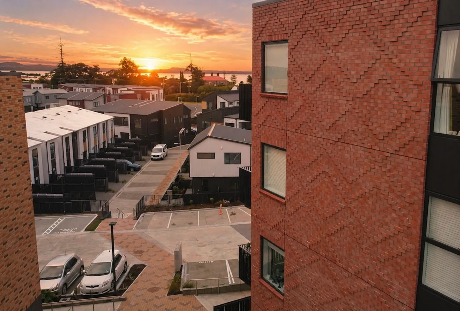 Completed medium-density housing development in Auckland at sunset, with brick apartments and terraced homes